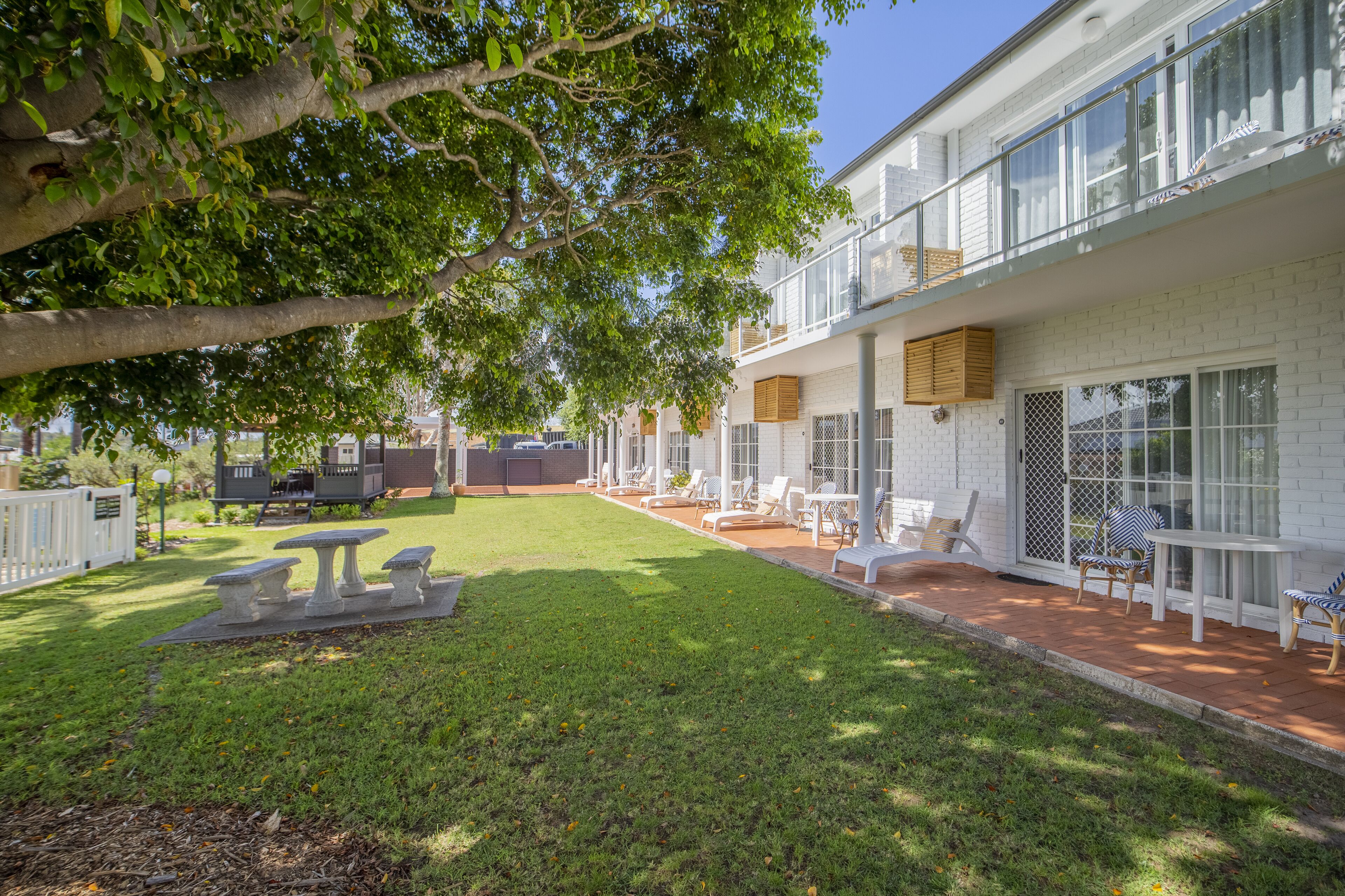A two-story building with a patio area featuring outdoor seating and a table.