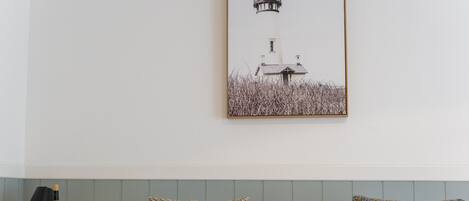 Une chambre d’hôtel avec un lit, une table de chevet, une lampe et un tableau représentant un phare.