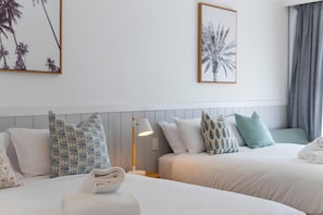 Ett hotellrum med två sängar, ett nattduksbord, en lampa och inramade konstverk på väggarna.