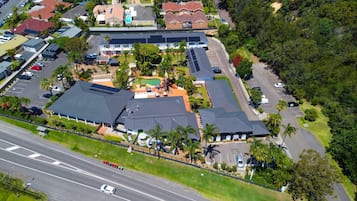 An aerial view of a residential area with multiple houses, a swimming pool, and a road.