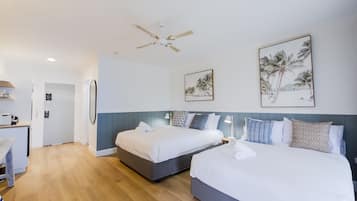 Habitación de hotel con dos camas, ventilador de techo y obras de arte en las paredes.