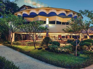A modern building with a curved facade, outdoor seating area, and well-maintained landscaping. - Mercure Convention Center Ancol (Jakarta)