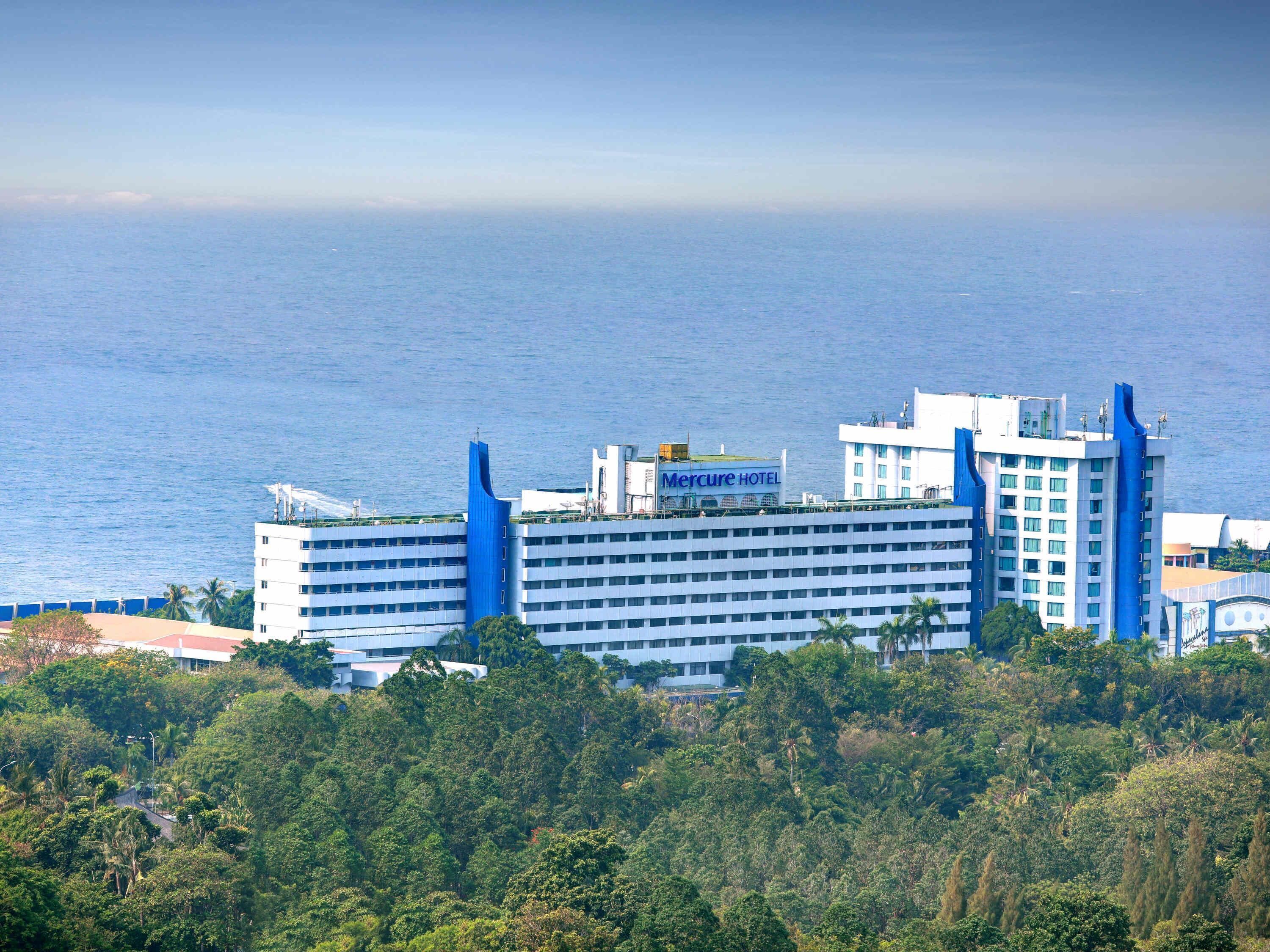 Un hotel con una imponente torre azul, varios pisos y vista al mar.