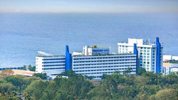 Un hotel con una imponente torre azul, varios pisos y vista al mar.