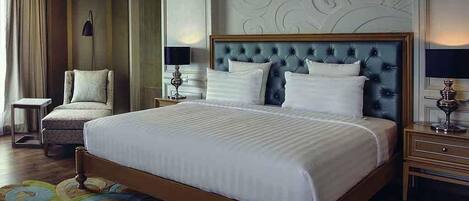 A hotel room with a large bed, a chair, a nightstand, and a lamp.