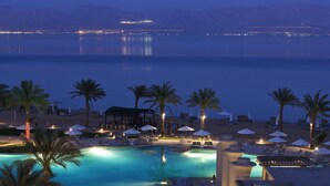 Ein Resort-Pool mit klarem Wasser, Palmen und Liegestühlen.