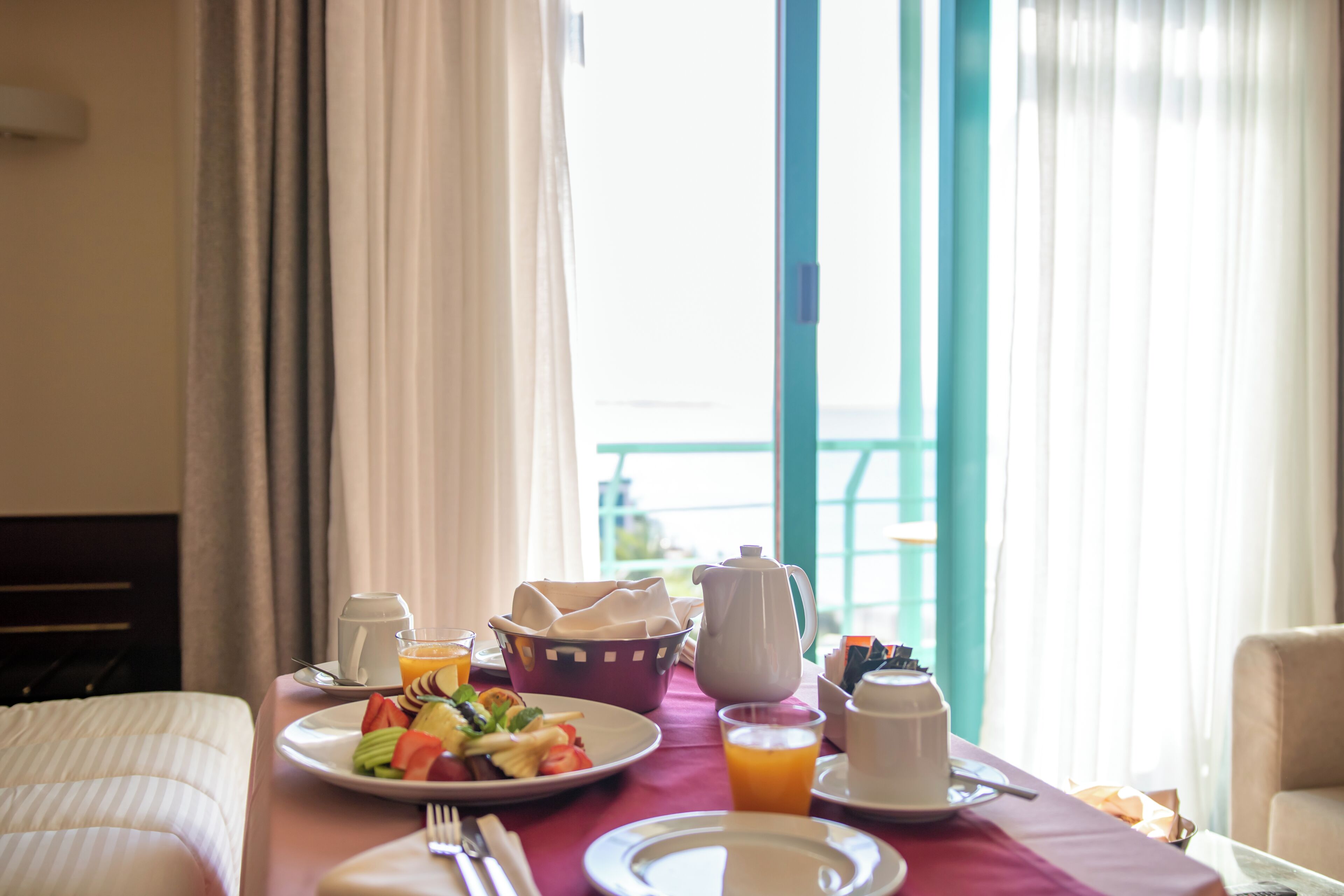 Une table de petit-déjeuner avec des assiettes remplies de nourriture, une carafe, une tasse et un verre de jus d’orange.
