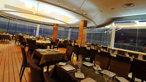A restaurant with tables set for dining, large windows, and a view of the cityscape.