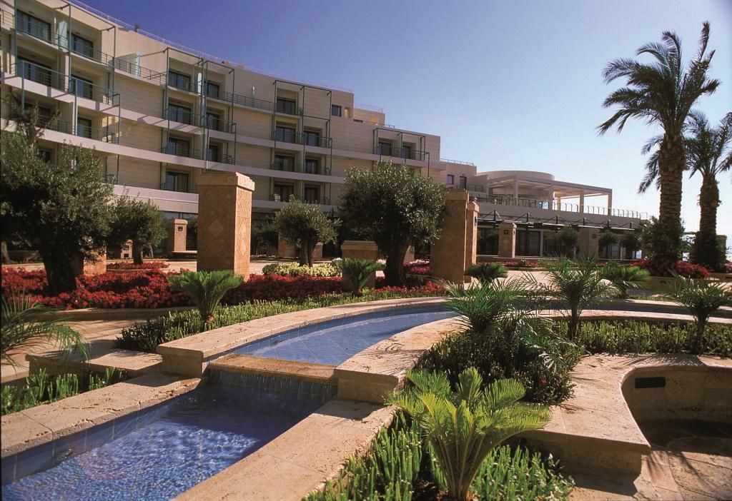 Ein Hotel mit Pool, Palmen und einem gepflegten Garten.