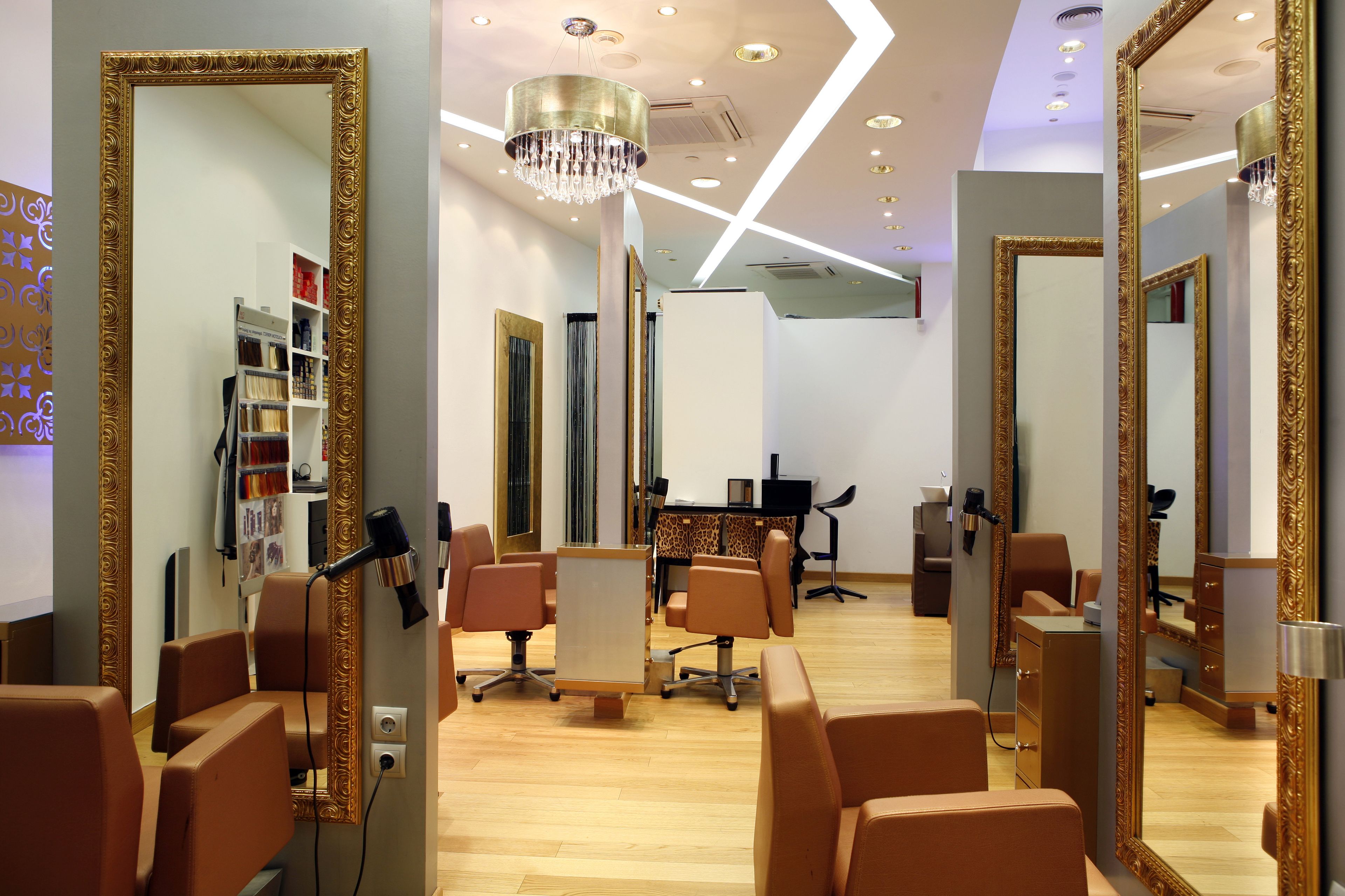 Un salón moderno con múltiples espejos, secadores de pelo y un mostrador central.