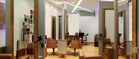 Un salón moderno con múltiples espejos, secadores de pelo y un mostrador central.