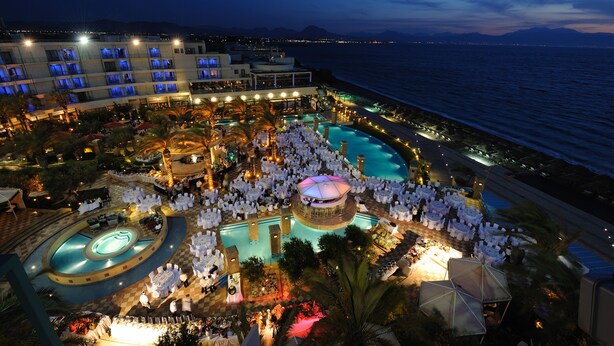 A resort with multiple swimming pools, a beachfront, and a large building with balconies.