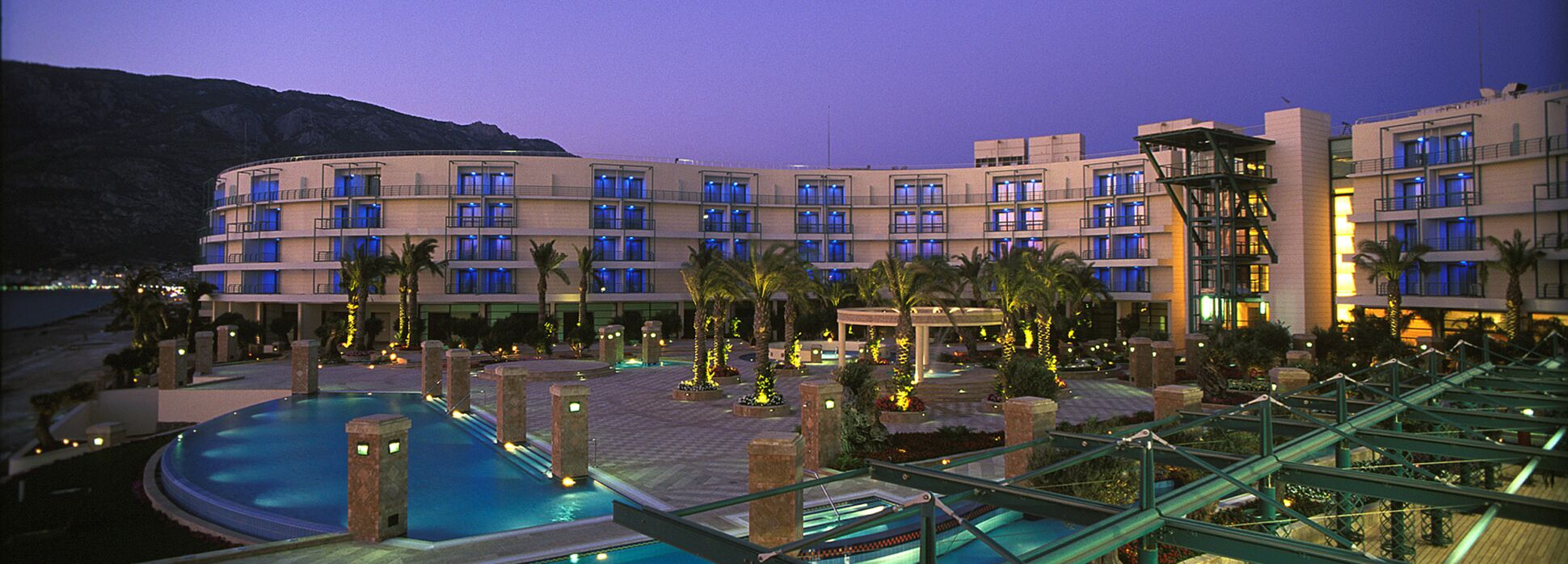 Un hotel con varios pisos, piscina y palmeras.