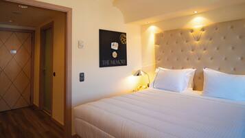 Habitación de hotel con una cama grande, un cabecero con diseño acolchado, una obra de arte en la pared titulada 'THE MEMORY' y una puerta con un patrón geométrico.