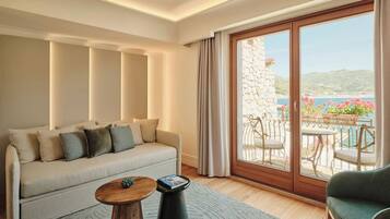A living room with a sofa, a coffee table, and a view of a balcony with outdoor furniture.