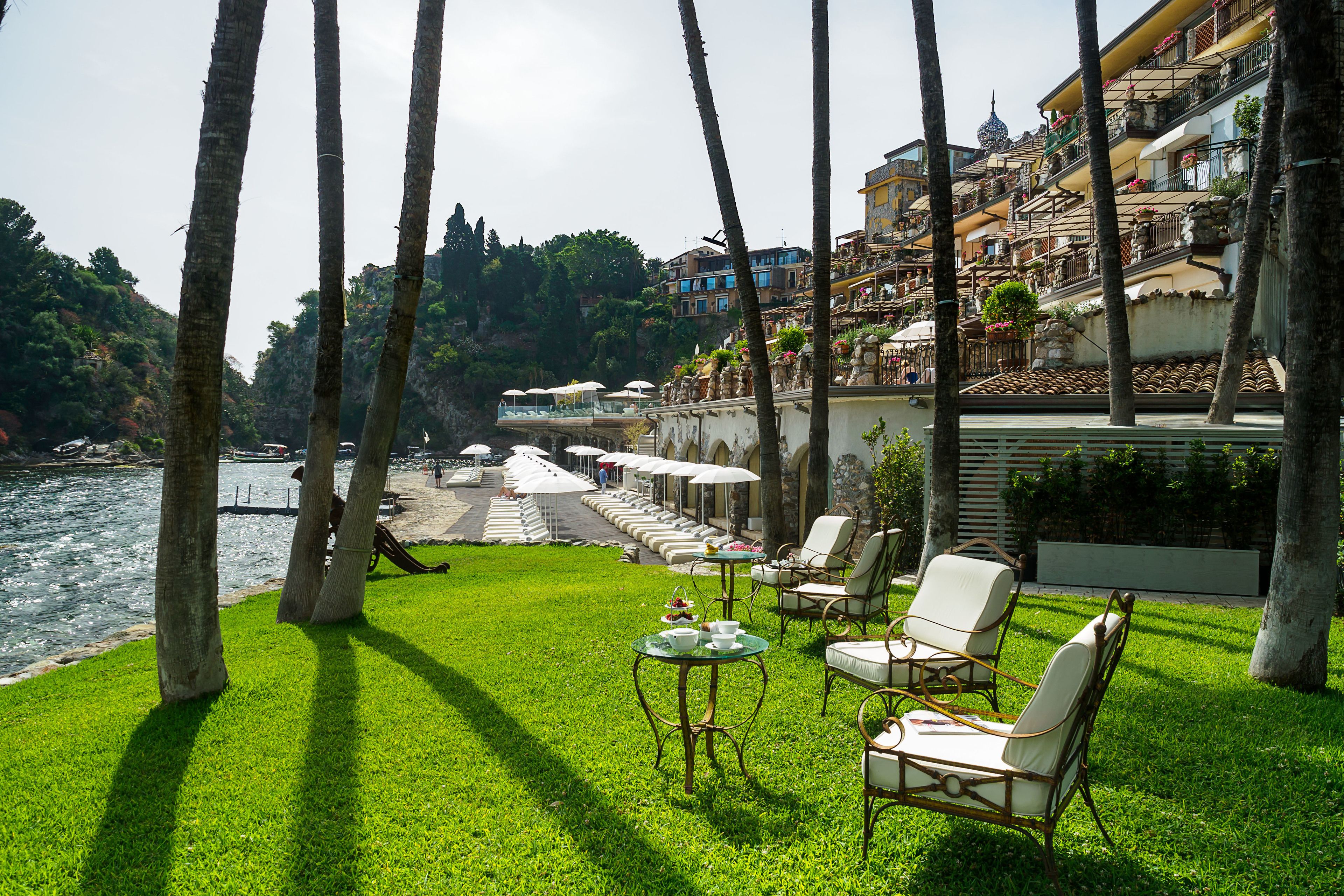 Una terraza con asientos al aire libre, con vistas a un río y una colina con edificios.