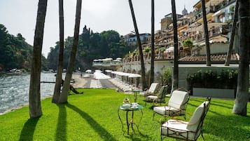Una terraza con asientos al aire libre, con vistas a un río y una colina con edificios.