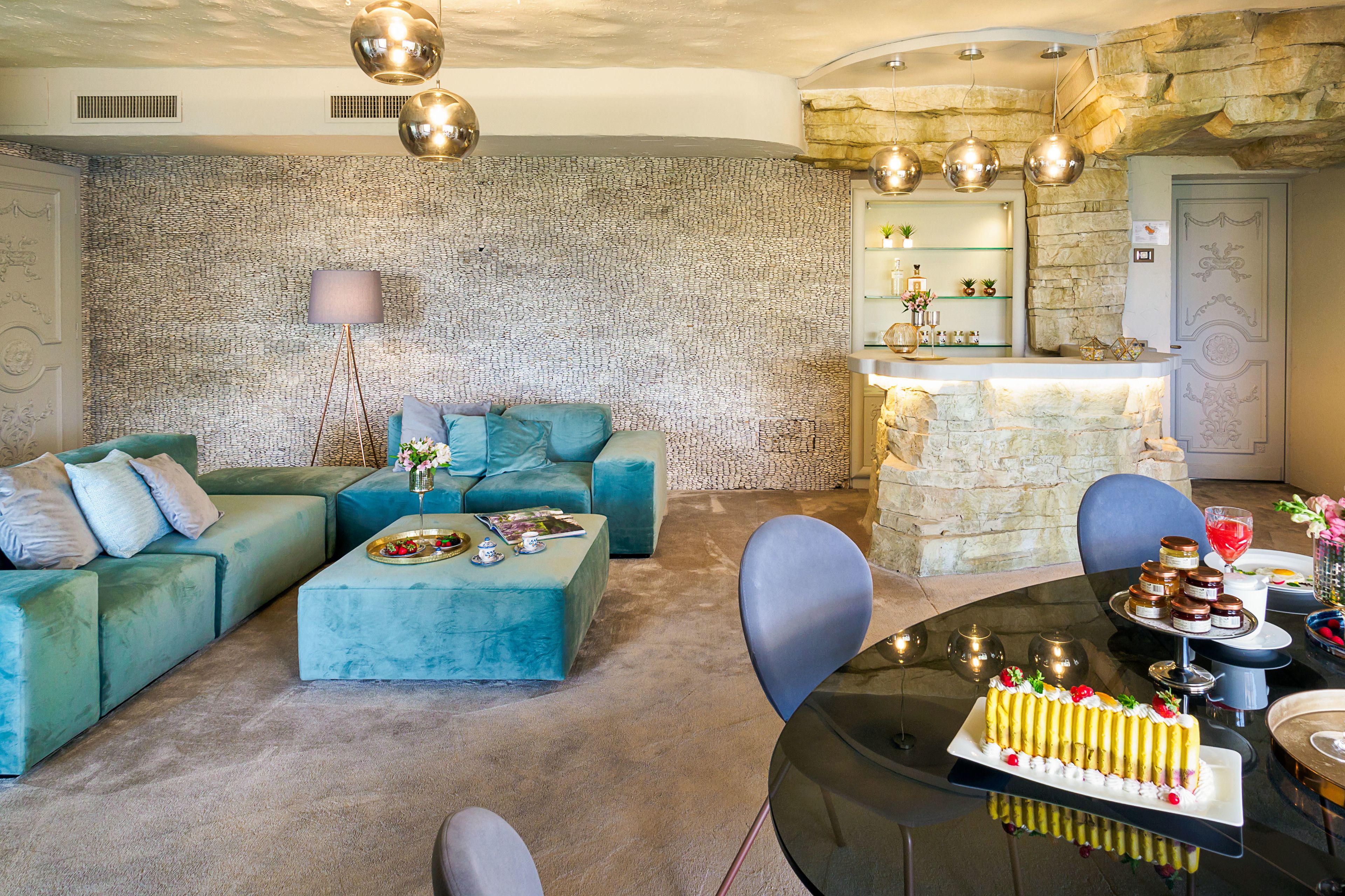 Un salon moderne avec un canapé, une table basse et un coin repas où l’on aperçoit un gâteau et des verres.