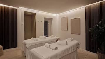 A spa room with two massage tables, a potted plant, and a framed artwork on the wall.