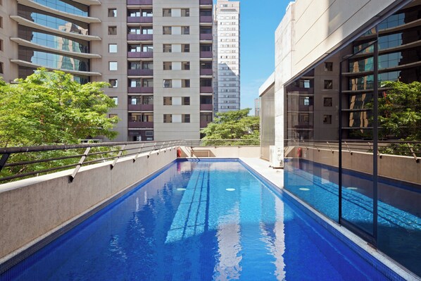 Une piscine offrant une vue sur les immeubles de grande hauteur et les arbres.