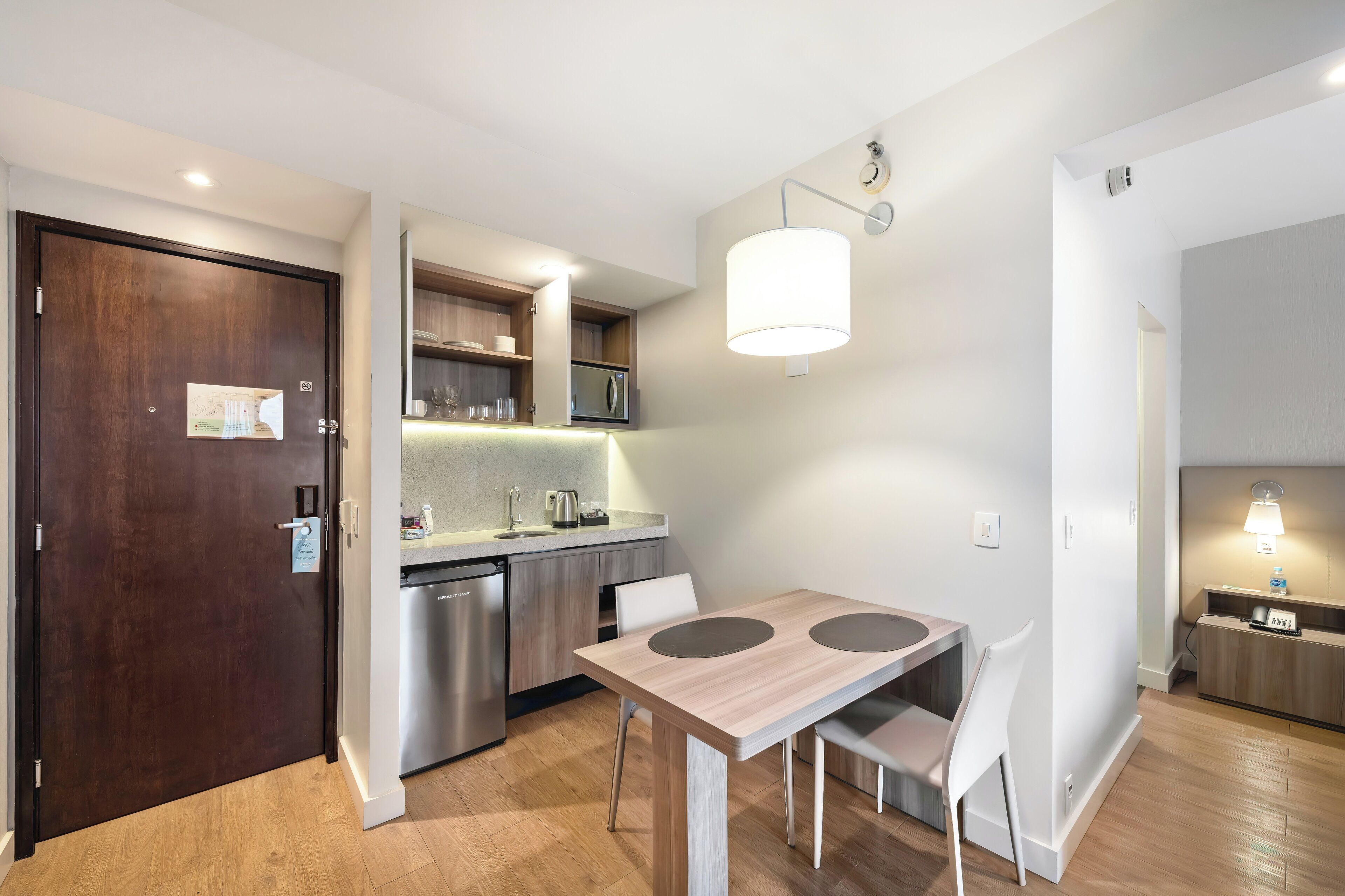 Una cucina moderna con tavolo e sedie in legno, elettrodomestici integrati e una lampada a sospensione.