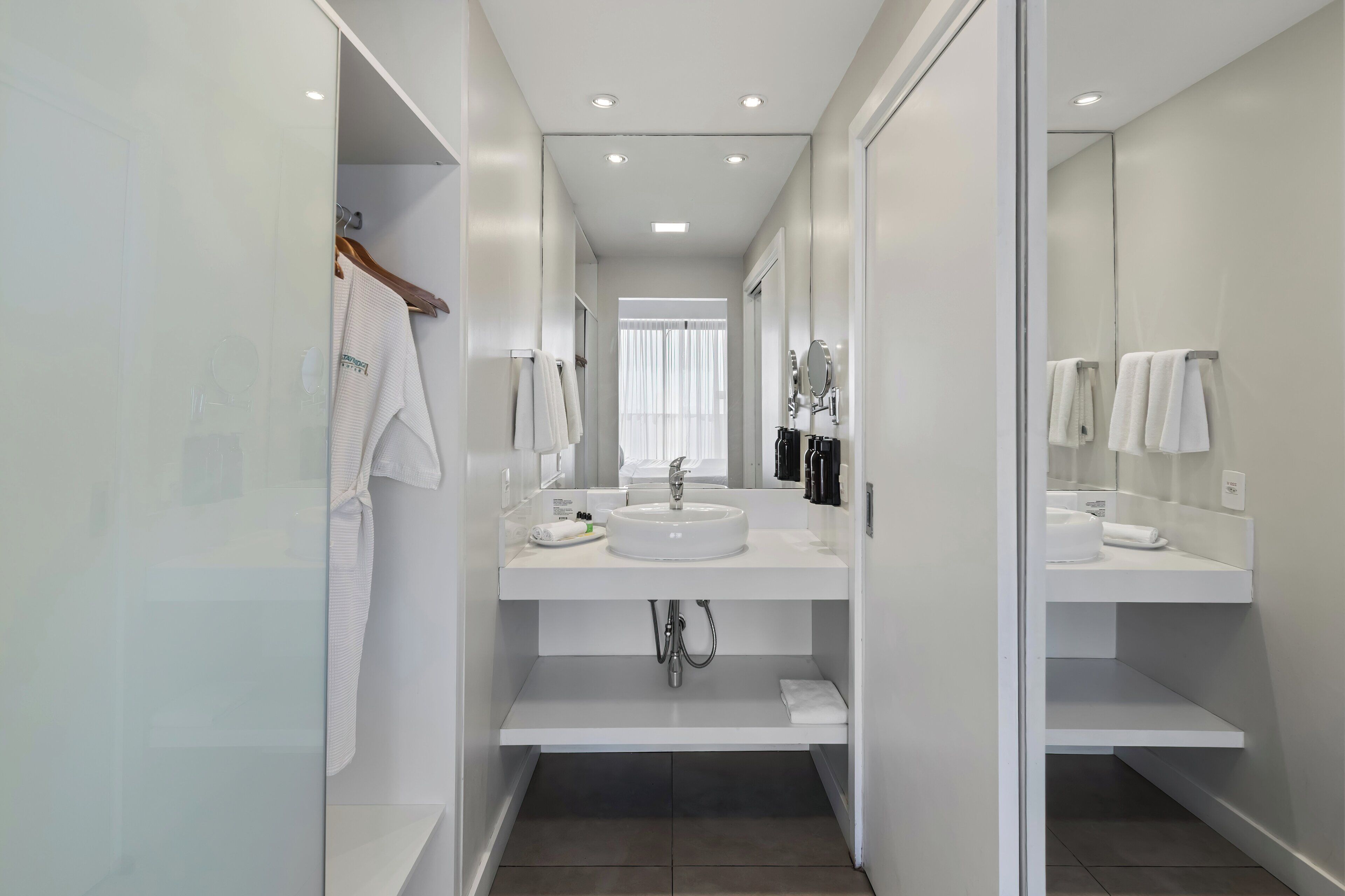 A modern bathroom with a central sink, a mirror, and a towel rack.