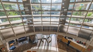 Un moderno vestíbulo con techo de vidrio curvo, una recepción, zona de estar y vistas a la ciudad.