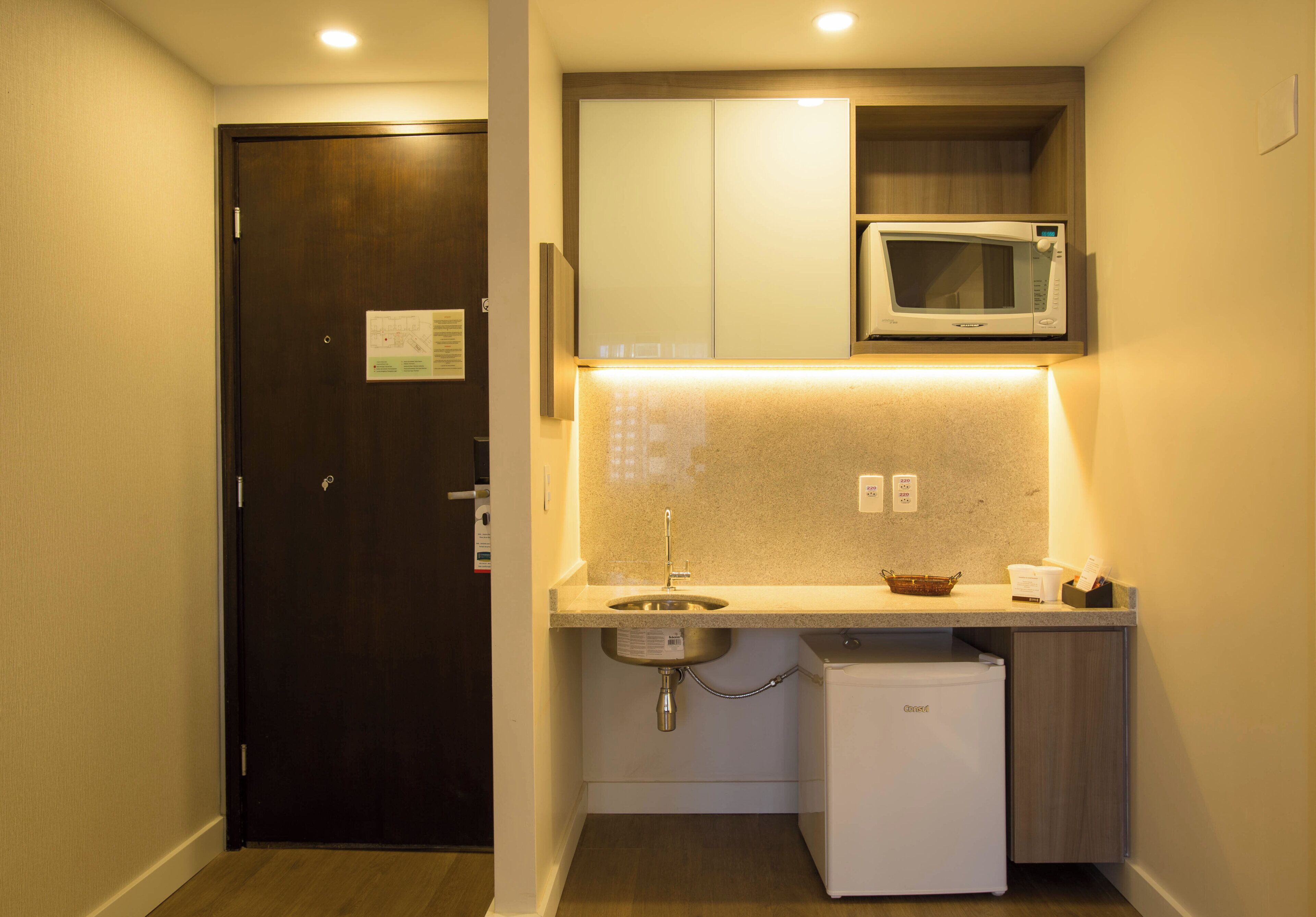 A compact kitchenette with a microwave, sink, and small refrigerator.