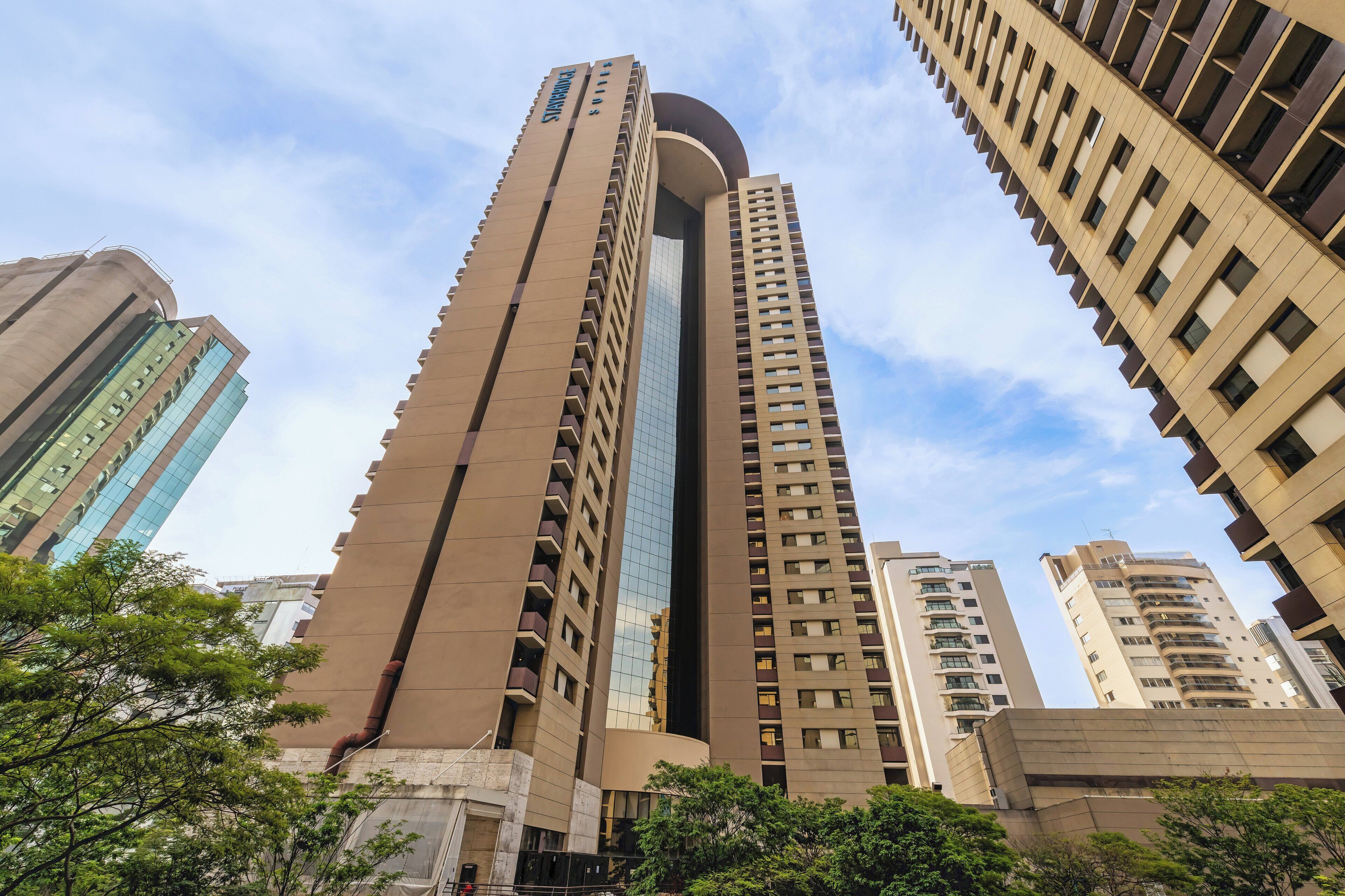 A tall, modern building with a curved facade and multiple balconies.