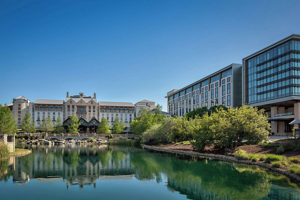 A hotel with a large building, a pond, and greenery.