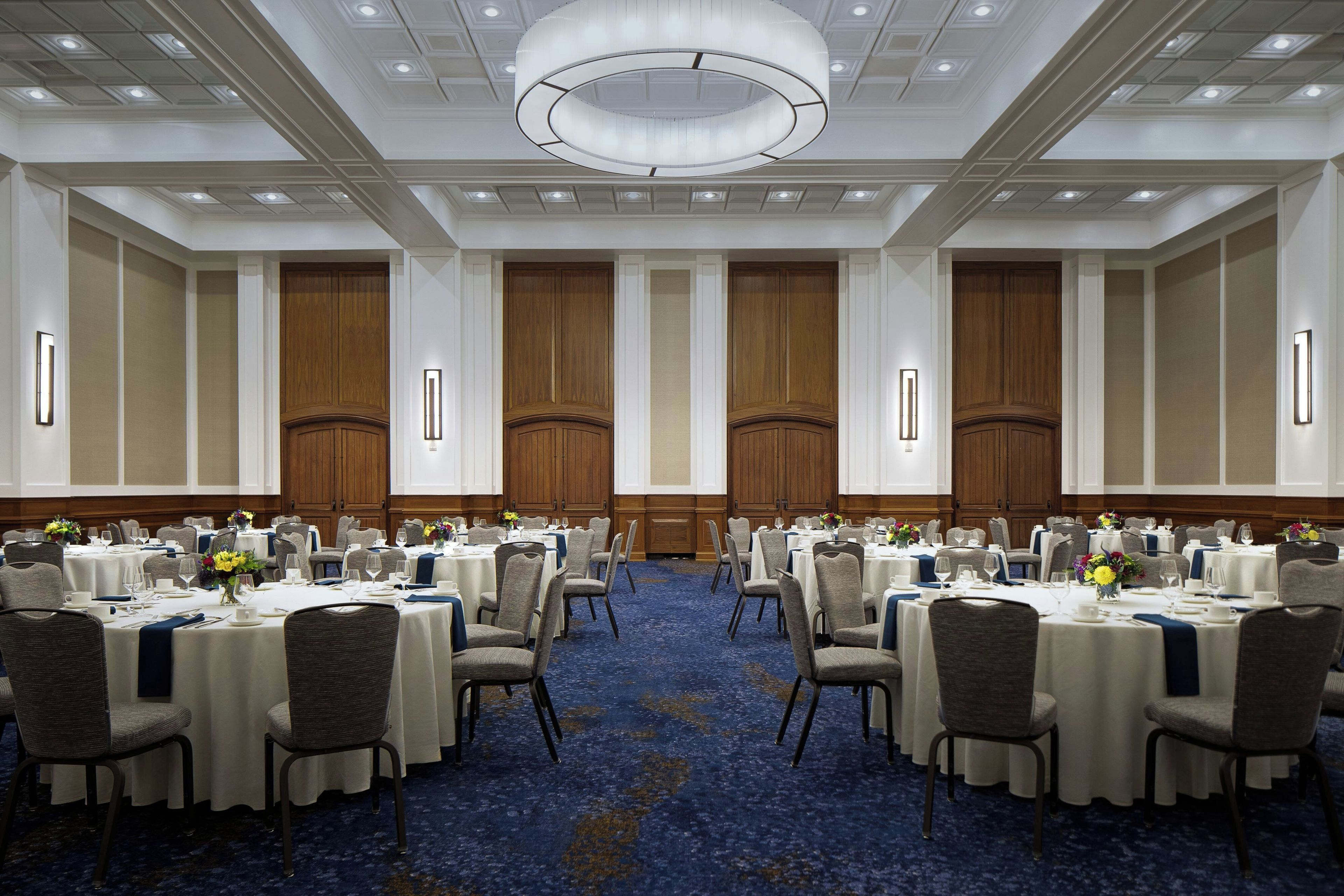 A conference room with round tables, chairs, and a blue carpet.