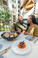Una mesa de comedor con diversos platos, incluyendo un tazón de carne y verduras, un plato con pulpo y un cóctel.