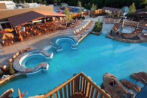 A resort pool area with a winding water feature, lounge chairs, and a covered seating area. - Gaylord Texan Resort & Convention Center (Grapevine)