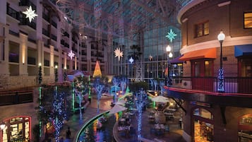 En hotellobby med ett glastak, flera våningar och juldekorationer, inklusive ljus och stjärnformade prydnader.