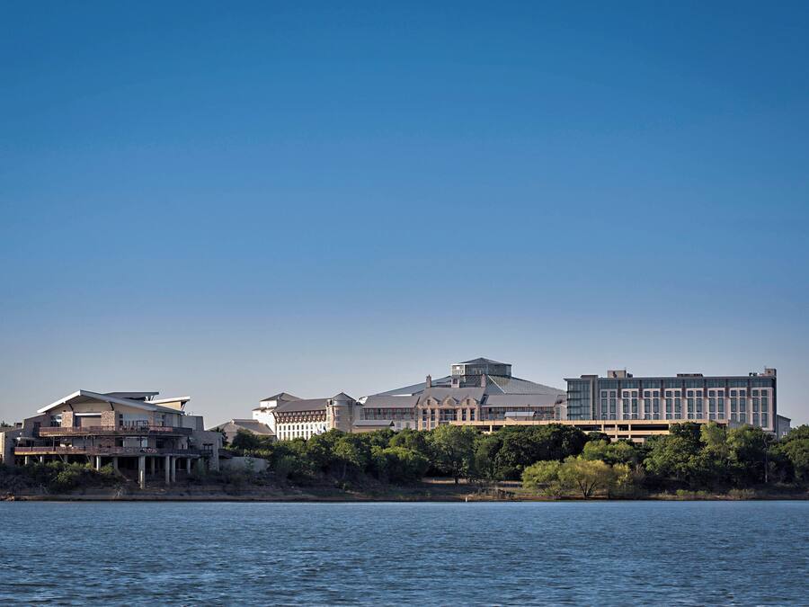 A waterfront hotel with multiple buildings, including a large central structure with a flat roof and smaller buildings with sloped roofs.