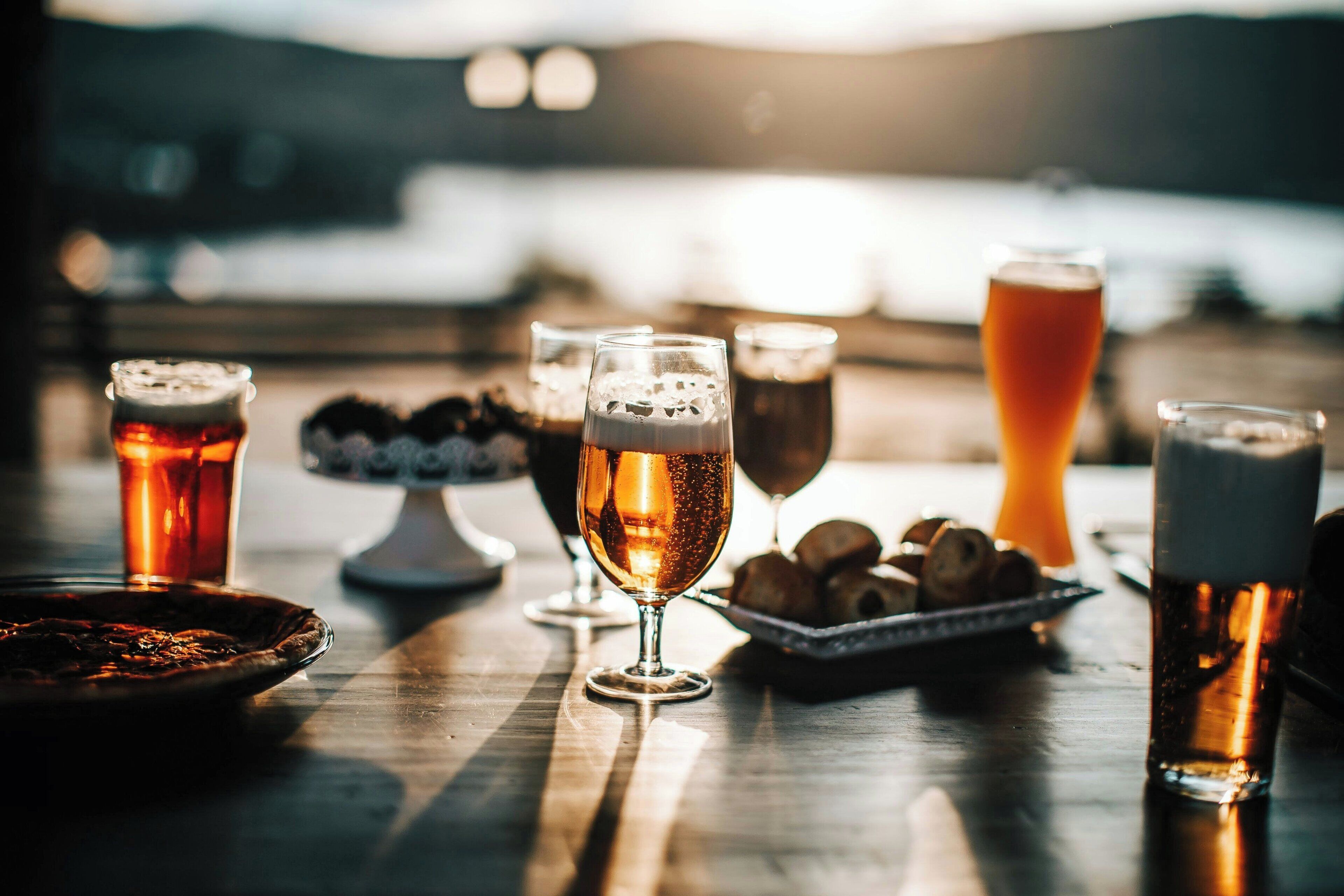 A table with various glasses of beer and pastries, suggesting a casual dining setting.