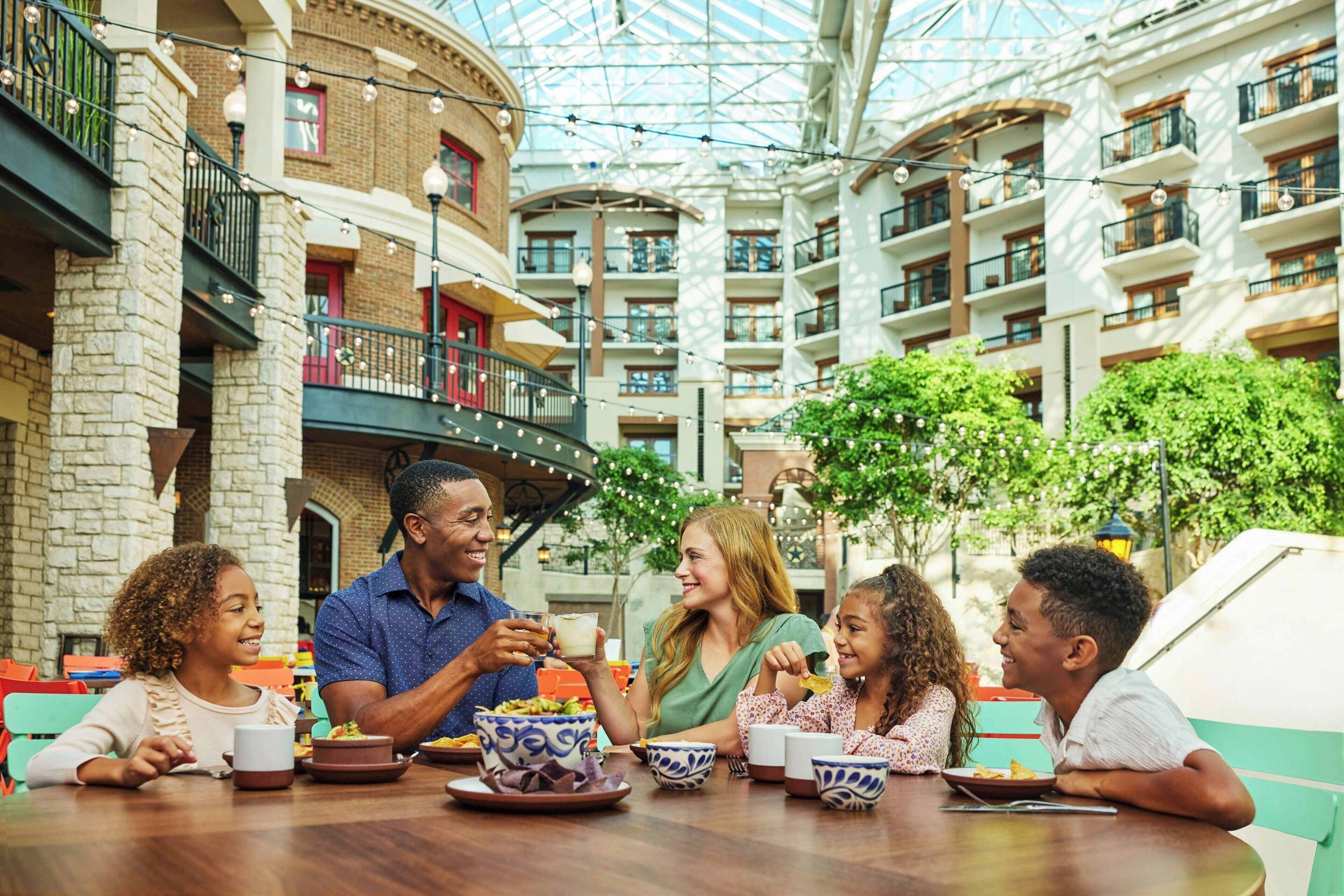 A family dining in a hotel atrium with a high ceiling and multiple balconies.