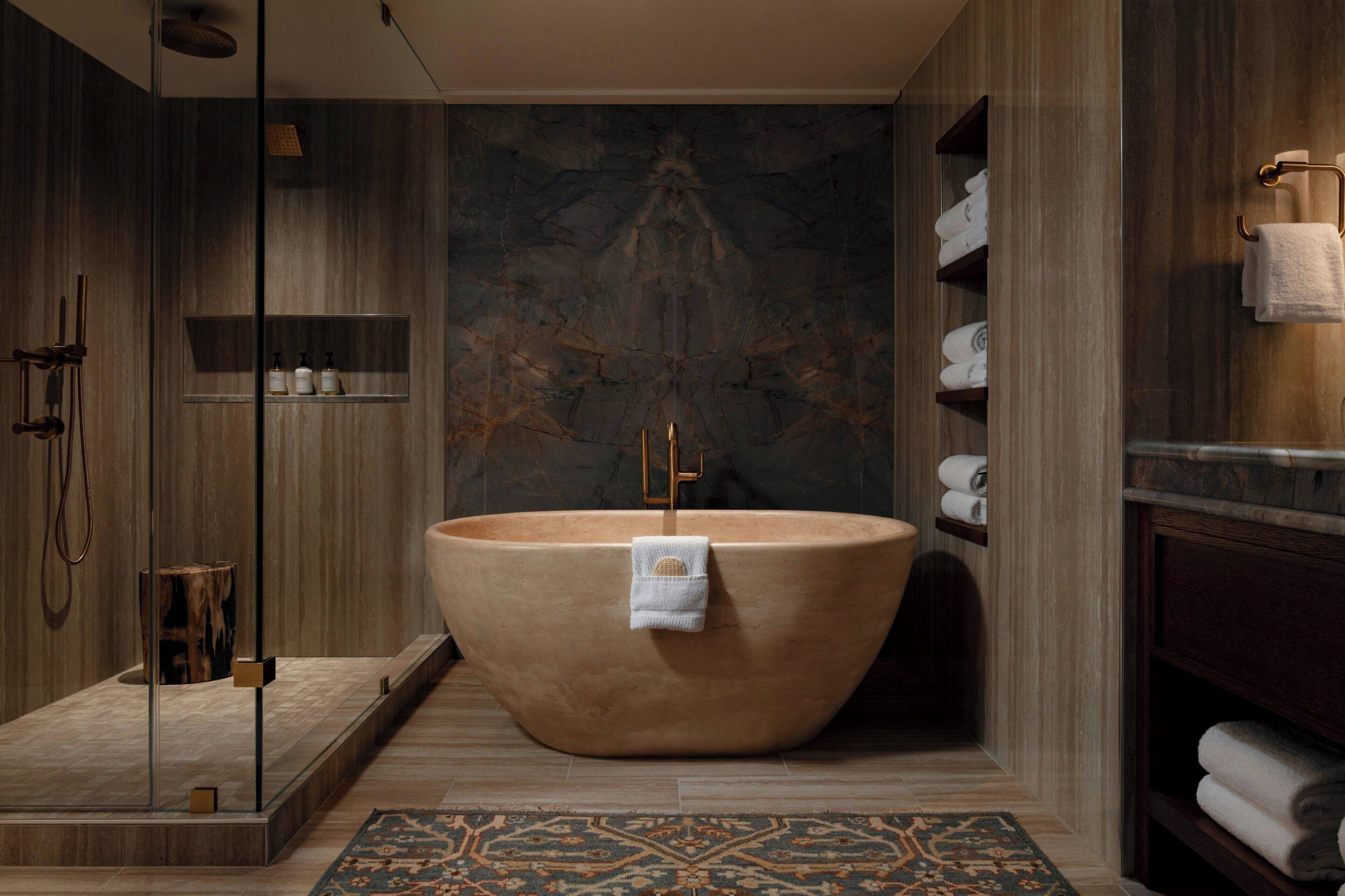 Un baño moderno con una bañera independiente, cabina de ducha con mampara de vidrio y tocador de madera con toallas.