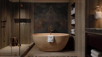 A modern bathroom with a freestanding bathtub, a glass shower enclosure, and a wooden vanity with towels.