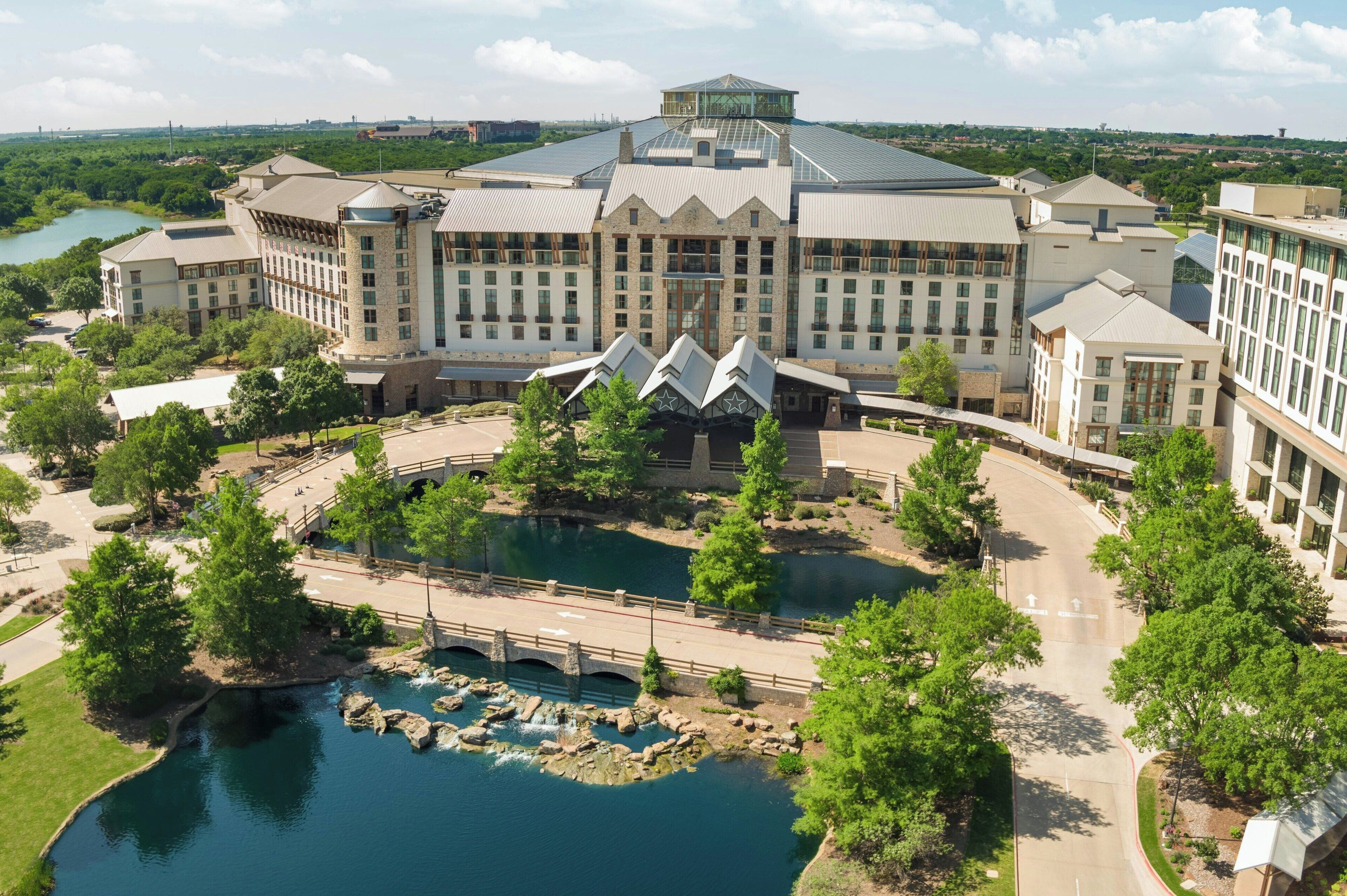 A large hotel with a central courtyard, a bridge, and a lake.