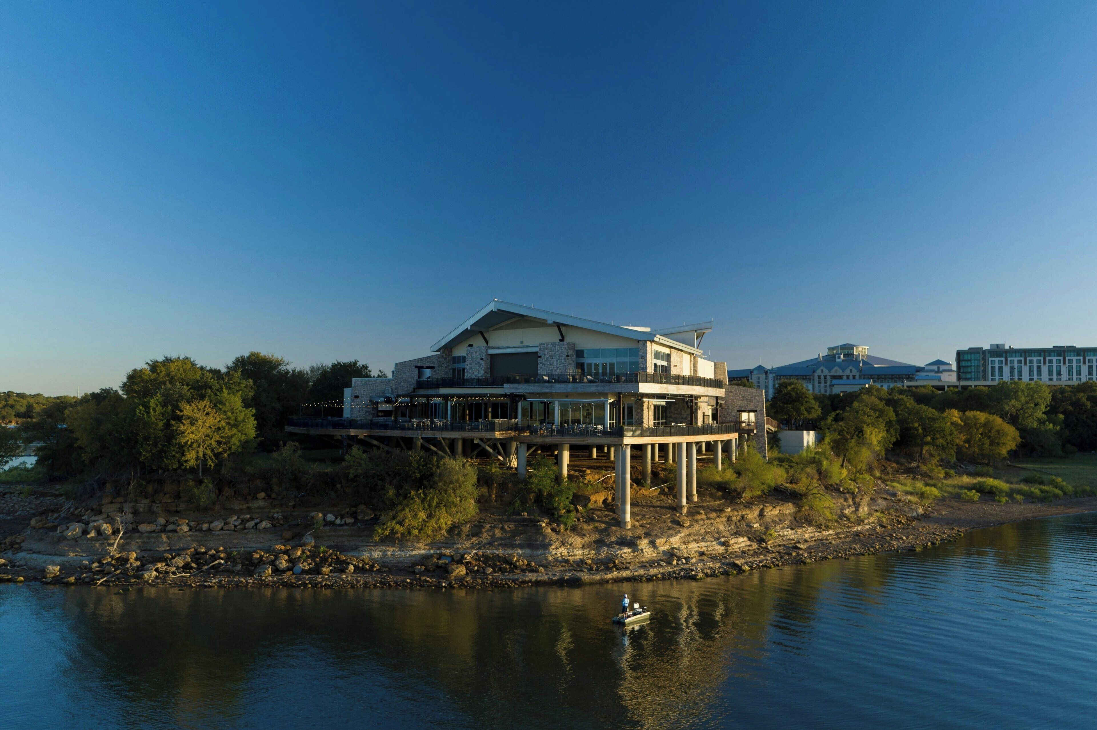 A modern house with a large balcony, situated by a river.