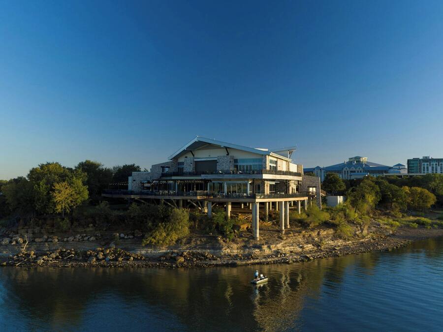 A modern house with a large balcony, situated by a river.