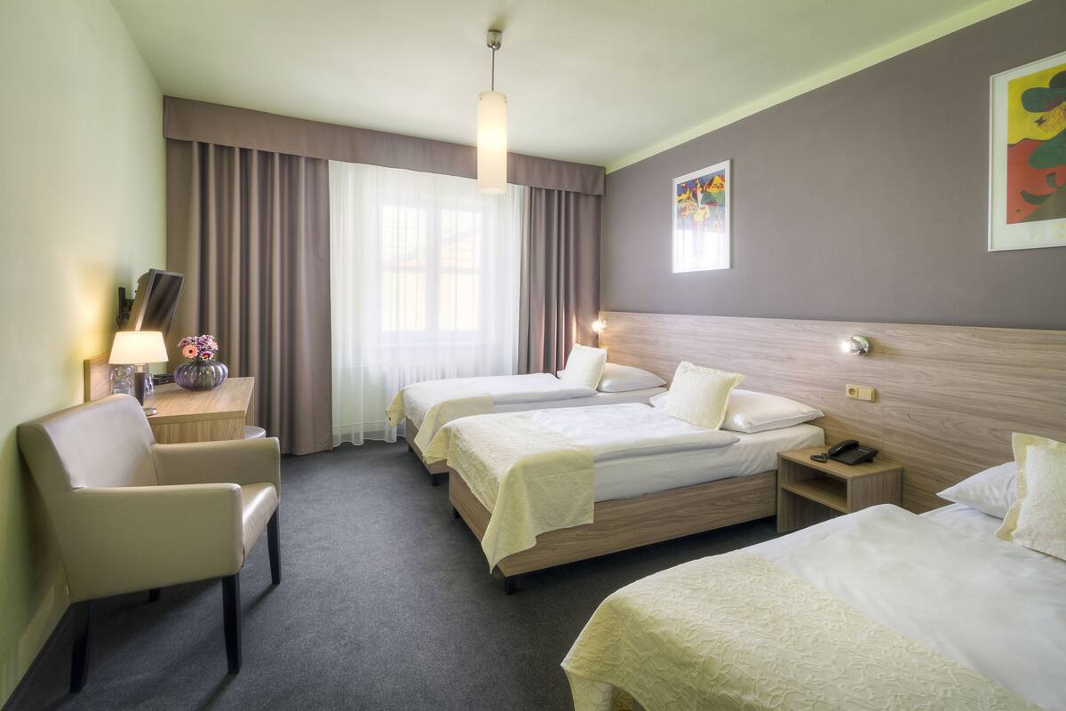 Una habitación de hotel con dos camas, un escritorio, una silla y una mesita de noche.