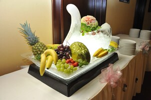 Un espositore di frutta e ghiaccio su un tavolo con un vaso decorativo e un bouquet di fiori.
