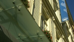 A building facade with a sign for Hotel Atlantic, featuring classical architecture with decorative moldings and flower boxes. - Atlantic Hotel (Prague)