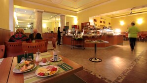 A hotel lobby with a buffet area, seating arrangements, and a reception desk. - Atlantic Hotel (Prague)