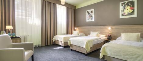A hotel room with two beds, a chair, a lamp, and a radiator.