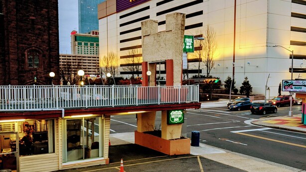 A Hard Rock hotel with a parking lot, a small building with a sign, and a street with cars. - Atlantic Motor Inn (Atlantic City)