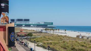 A beachside view with a boardwalk, beach, and a large building in the background.
