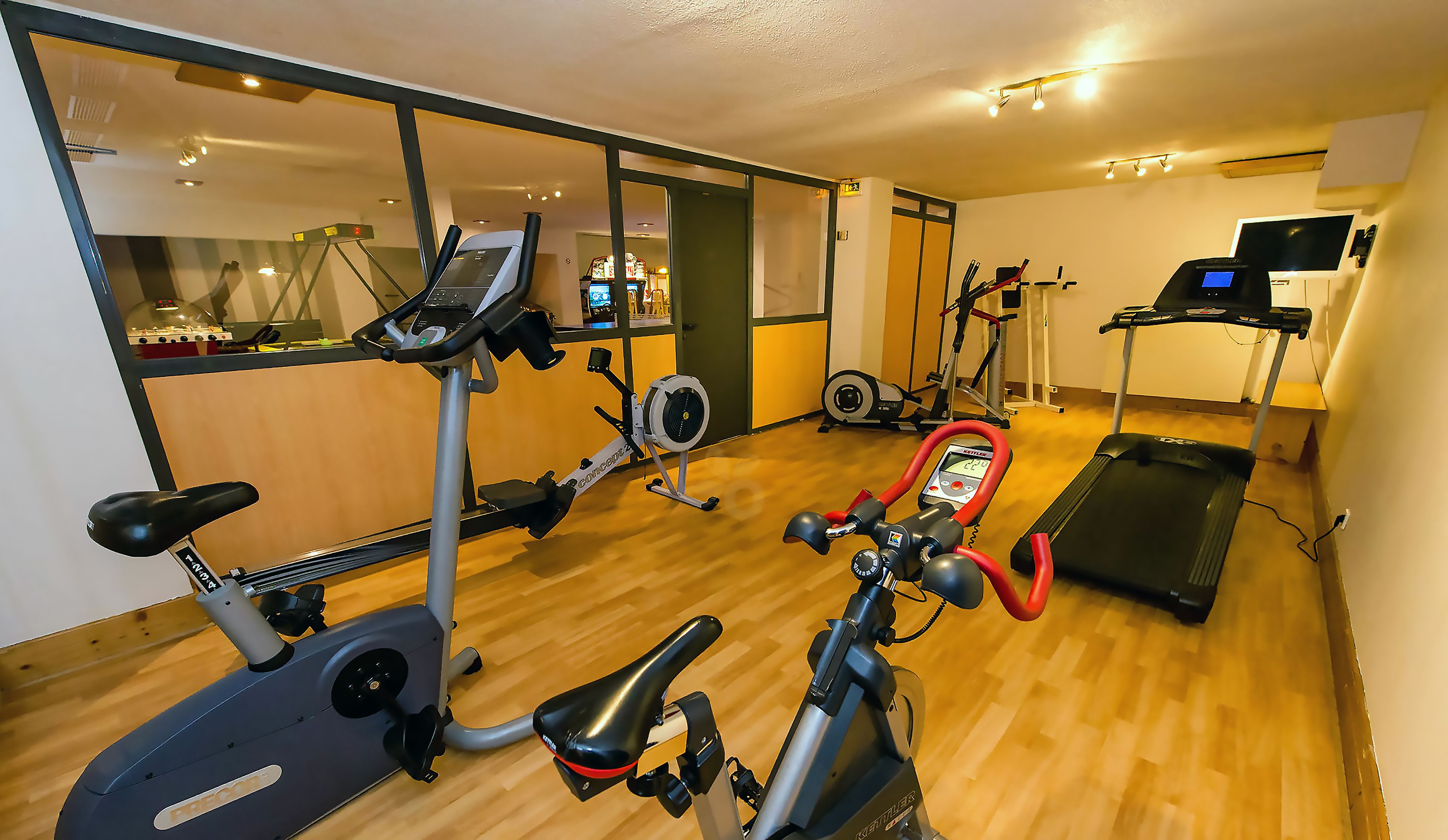 Un gimnasio en casa con equipo de ejercicio, incluyendo una elíptica, bicicleta estática y caminadora.
